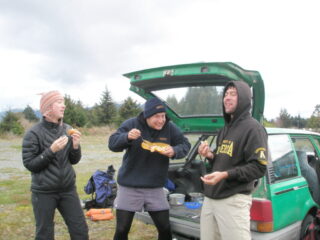 A man shows off his cooked eggs while his friends look dismayed.