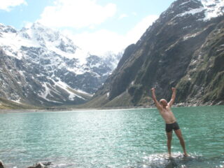 A man celebrates the beauty of an alpine lake.