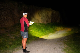 A man uses a map and compass at night