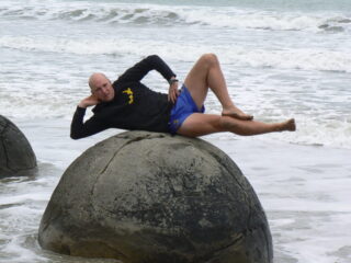 A man planks on a Moeraki boulder.