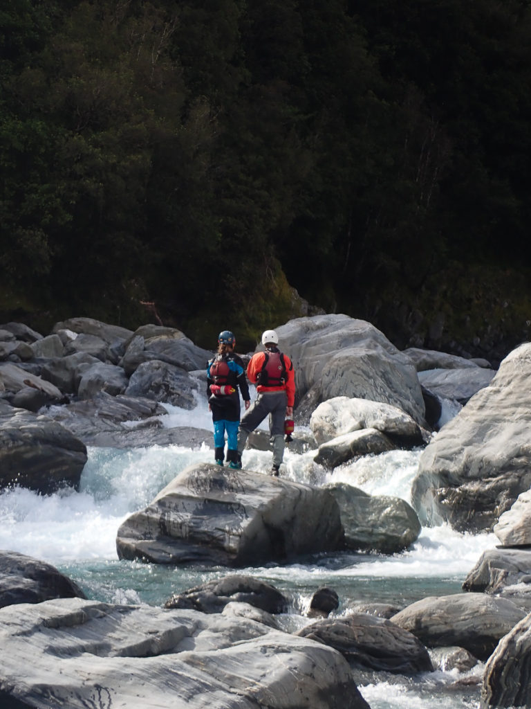 Two packrafters scout a rapid on the west coast